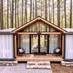 The Canopy container home with a central glass gable great room between two container wings and solar panels
